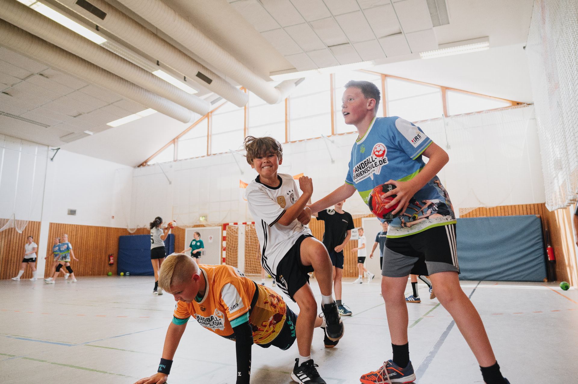 Trainer und Kinder beim betreuten Handballtraining in der Halle
